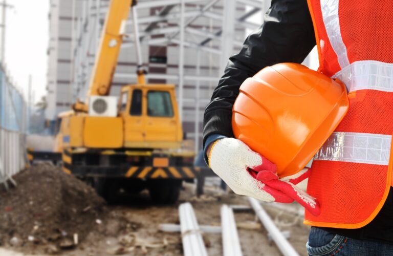 Construction worker in hi-vis safety vest holding a hard hat